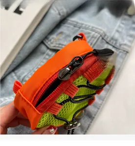 Detail of vibrant orange nylon and green mesh mini bag with smooth metal zipper