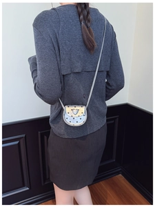 Rear view of a girl wearing a silver mini heart crossbody bag with black polka dots