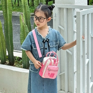 Mini borsa a tracolla per bambini rosa e beige indossata da una modella in ambiente esterno