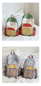 Detail of color-block school backpacks in vibrant green and subtle grey on white bedding