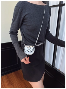 Detail of silver heart-shaped polka dot mini crossbody bag for kids shown on a model