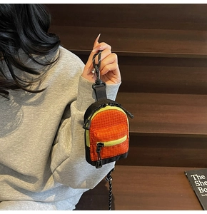 Détail du mini porte-monnaie sac à dos avec couleurs contrastées orange vert et texture