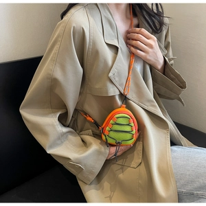 Mini orange and green mesh crossbody bag worn by a model in a trendy trench coat