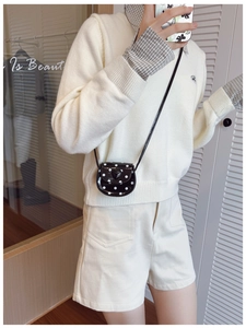 Close-up of black polka dot mini crossbody bag with heart buckle and glossy finish