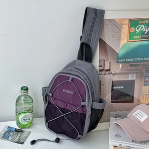 Detail of purple and gray nylon chest bag with front elastic cords and side mesh pockets