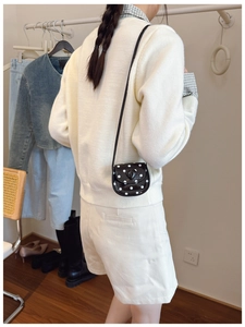 Close-up of mini polka dot shoulder bag with heart detail shown on a young girl