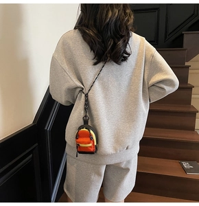 Vue détaillée du mini sac à dos orange attaché au dos du sweat à capuche gris pour enfant