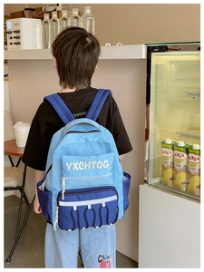 Outdoor back view of blue color-block kids backpack with adjustable padded straps