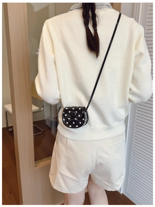 Polka dot mini crossbody bag with heart detail worn by child over a white sweater