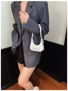 Detailed view of kids' mini white handbag with large bow accent worn by a young model