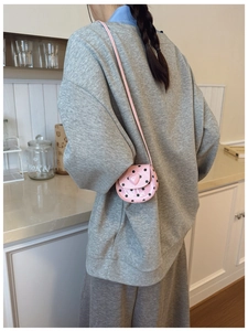 Detailed view of the pink heart-shaped buckle on a polka dot girls crossbody bag