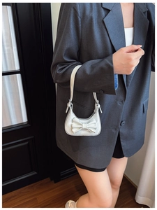 Detail showing white bow accent and glossy patent leather finish on kids handbag