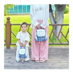 Detail of matching parent-child checkered backpacks with cute bunny motif in blue and white
