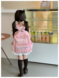 Pink school backpack with adjustable straps worn by a child in a cozy cafe setting