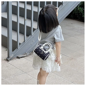 Détail d'un mini sac cylindre pour filles avec broderie nœud et pendentif en cœur