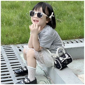 Détail d'un sac polochon pour enfant noir et blanc avec nœud et pendentif cœur