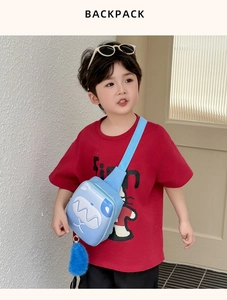 Detail of light blue kids chest bag with cartoon monster face and plush ball charm
