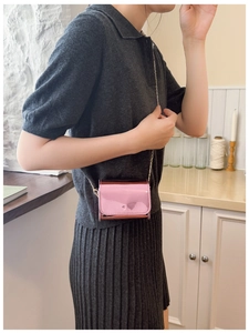 Close-up of mini pink metallic crossbody bag with gold chain strap on a model