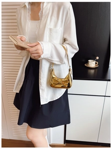Detail of laser mirror kids' handbag featuring a large bow and glossy gold finish