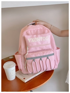 Detail of pink school backpack with letter print and safety reflective strip on a table