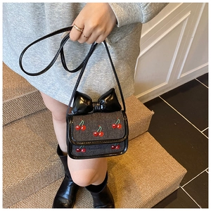 Détail du mini sac bandoulière en denim gris avec broderie cerise et un grand nœud papillon noir