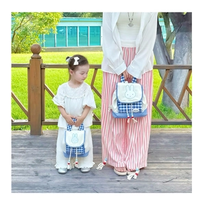 Outdoor shot of matching parent-child checkered canvas backpacks with bunny motifs