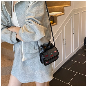 Détail du mini sac bandoulière avec broderie cerise rouge et un grand nœud noir décoratif