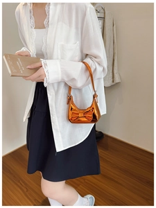 Detail of a bright orange metallic kids handbag with a large 3D bow and slim handle