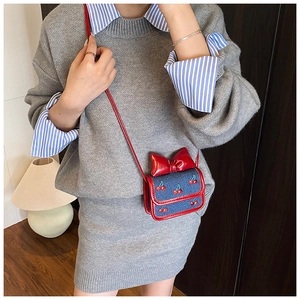 Détail du mini sac bandoulière en jean avec broderie cerise et un grand nœud rouge vif