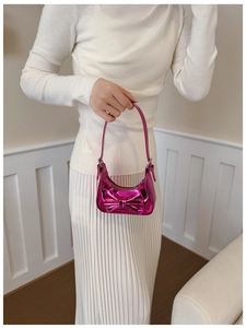 Detail view of metallic pink bow handbag with shiny mirror finish and zip closure