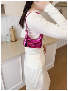 Detail of metallic hot pink kids handbag with oversized bow and shiny laser finish