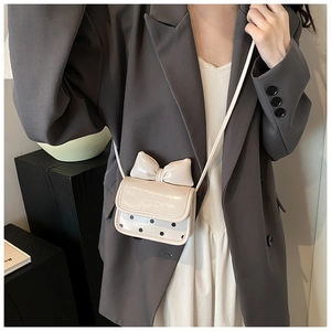 Mini cream crossbody bag with bow and polka dots, shown with chic blazer outfit