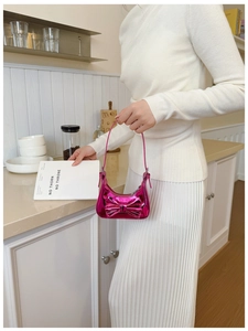 Close-up of metallic pink girls' handbag with large bow and Y2K aesthetic shine