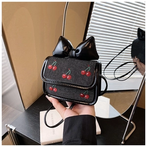 Close-up of black mini crossbody bag with cherry embroidery and large leather bow