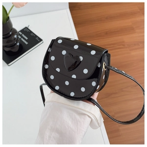 Detailed view of mini polka dot handbag with black heart accent and glossy finish