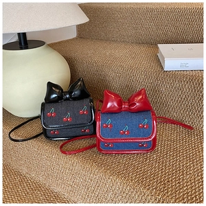 Mini crossbody bags with cherry embroidery and bow detail on decorative stairs