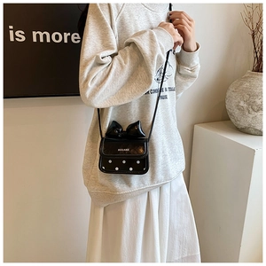 Detail of a mini black crossbody bag with a white polka dot pattern and a 3D bow design