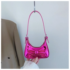 Macro detail of glossy metallic pink bow and laser mirror finish on small handbag