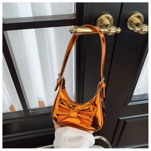 Metallic orange kids handbag with a 3D bow hanging on a golden door handle detail