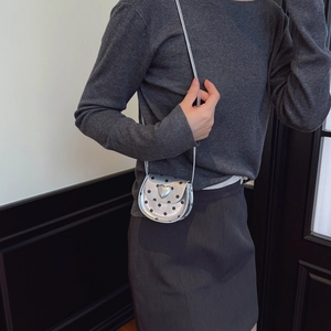 Silver mini crossbody bag with black polka dots and heart ornament on model