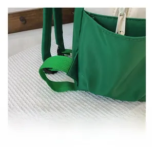 Detail showing the reinforced triangular stitching and green strap on the kid's backpack