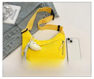 Flat lay of bright yellow hobo bag with moon plush charm and adjustable strap