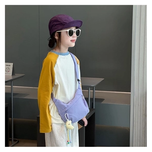 Detail of purple canvas half-moon bag for kids with adjustable strap and plush charm