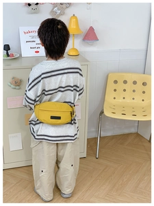 Dettaglio del marsupio per bambini in nylon giallo vivace su una maglietta a righe