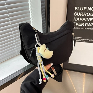 Detail of black crescent crossbody bag with colorful woven tassel and plush moon charm