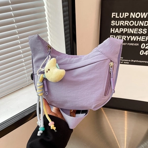 Detail view of a light purple crescent nylon bag with a plush moon pendant accessory