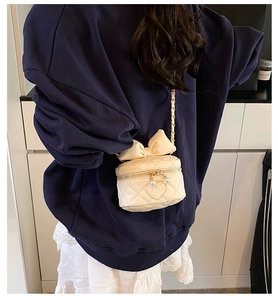 Detail of cream quilted crossbody bag with oversized bow and pearl heart zipper charm