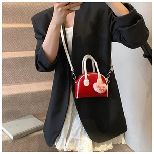 Close-up of mini red shell bag with white handle and Barbie Girl heart charm pendant