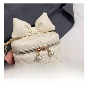 Close-up of cream mini bucket bag featuring a large bow and pearl zipper charms