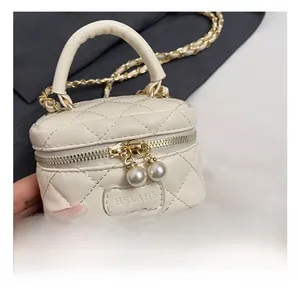 Close-up of cream mini quilted crossbody bag with pearl zipper detail and gold chain